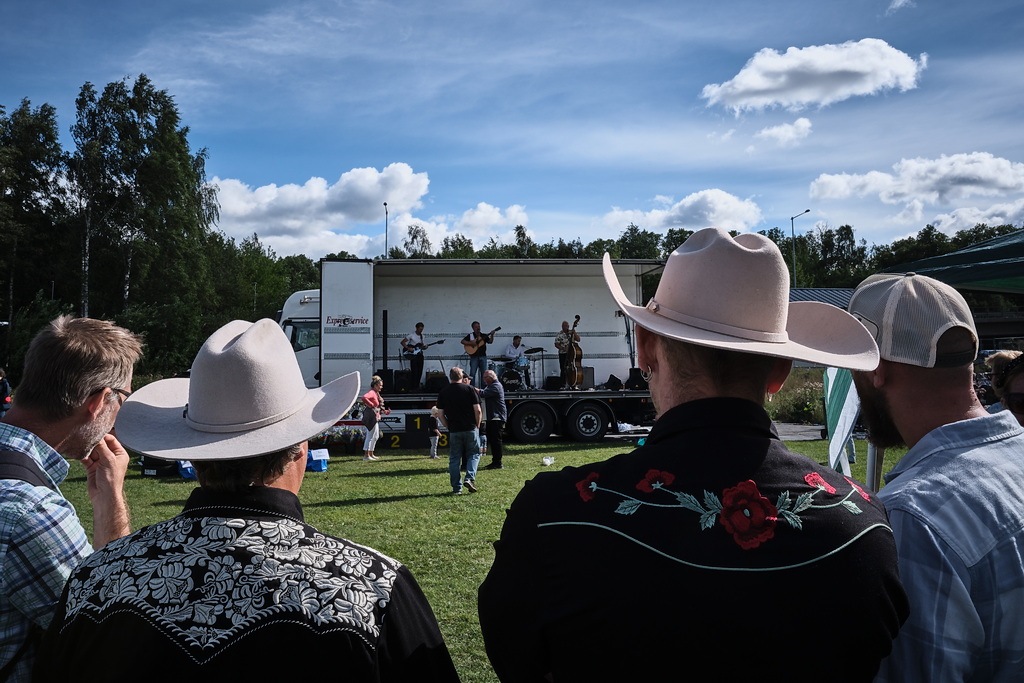 Män i cowboy hätter som tittar på ett band som spelar musik på ett släp